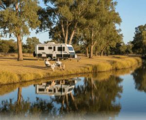 Grey nomad couple at free riverside camping Queensland beside an outback river with caravan parked on flat ground
