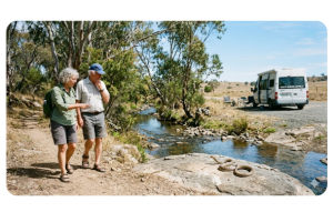 Grey Nomad and snakes in Australia – senior vanlifers walking near bush campsite while watching for snakes in grass and rocky ground at an outback camping area