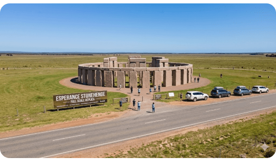 Esperance Stonehenge replica on Merivale Road WA, pink granite standing stones, flat surrounding landscape, visitors exploring site.